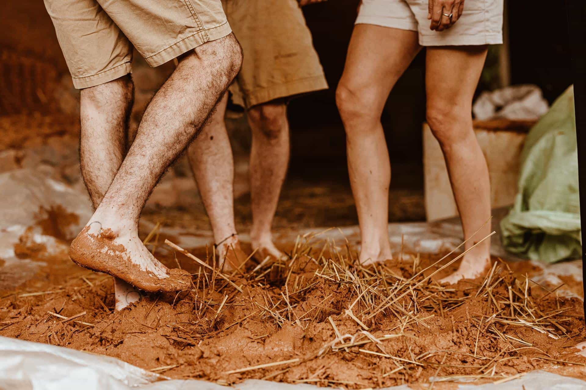 Bare legs and feet treading clay during a family building day