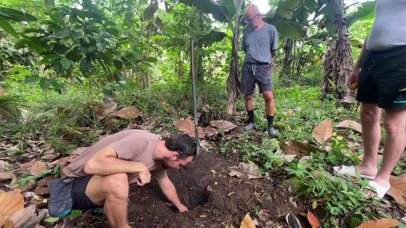 Michael placing an offering into the ground while another man stands nearby in the forest