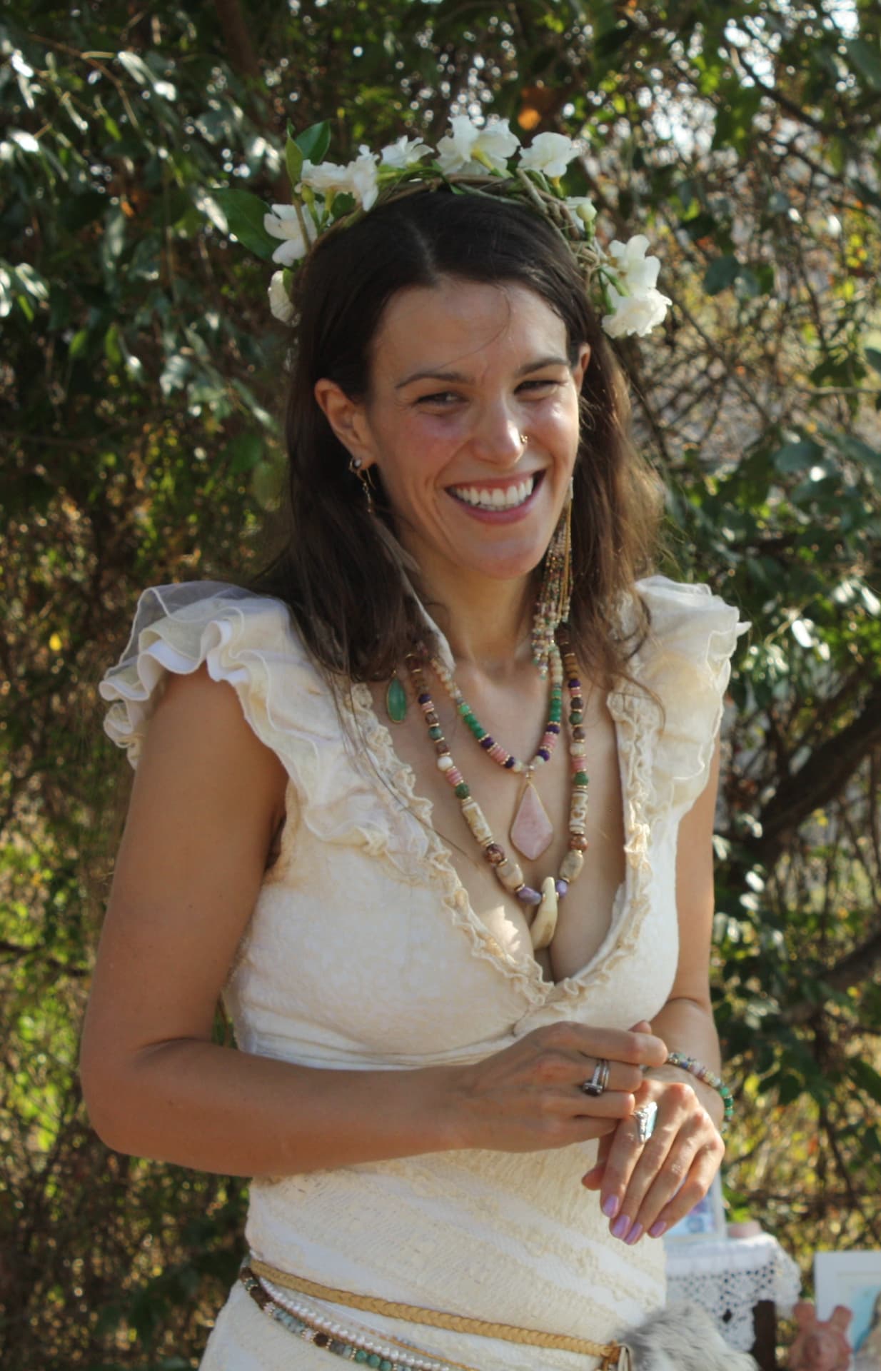 Yara smiling outdoors, wearing a flower crown and beaded necklaces